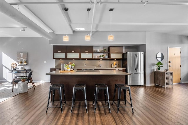 kitchen featuring a kitchen bar, a center island, hanging light fixtures, dark brown cabinets, and stainless steel refrigerator