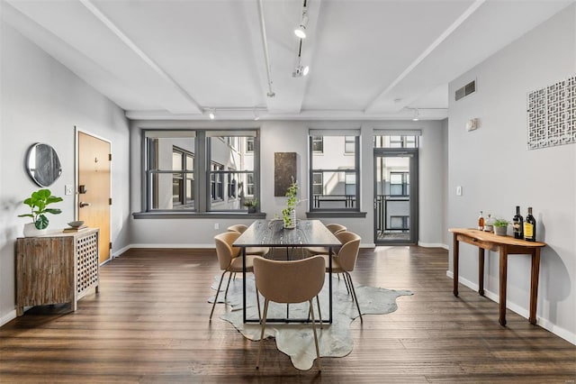 dining room with dark hardwood / wood-style floors and rail lighting