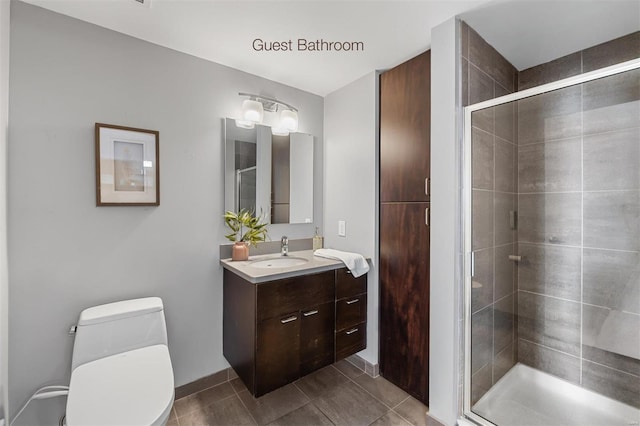 bathroom featuring a shower with door, vanity, tile patterned floors, and toilet