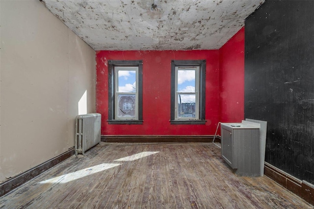 unfurnished room featuring wood-type flooring and radiator heating unit