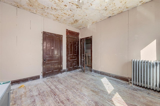 unfurnished room featuring radiator heating unit and wood-type flooring