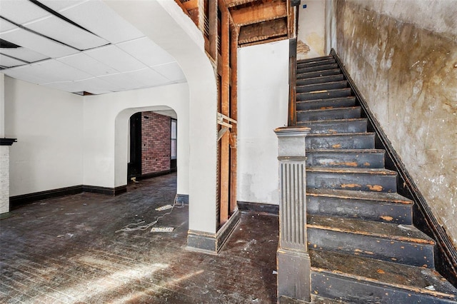 stairway featuring a drop ceiling