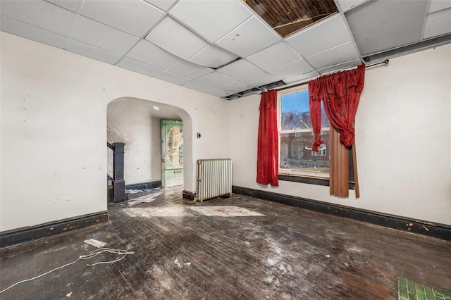 empty room featuring a drop ceiling and hardwood / wood-style flooring