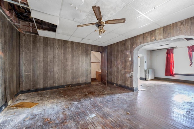 empty room with hardwood / wood-style flooring, a paneled ceiling, and wooden walls