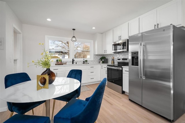 kitchen with white cabinetry, tasteful backsplash, stainless steel appliances, and hanging light fixtures