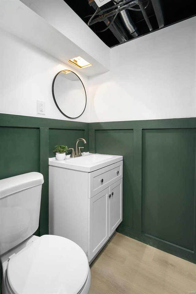 bathroom featuring wood-type flooring, toilet, and vanity