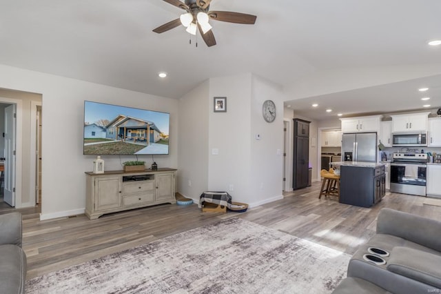 living room featuring lofted ceiling, light hardwood / wood-style flooring, and ceiling fan