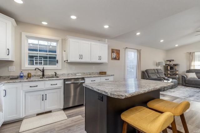 kitchen with white cabinetry, stainless steel dishwasher, a kitchen breakfast bar, and sink