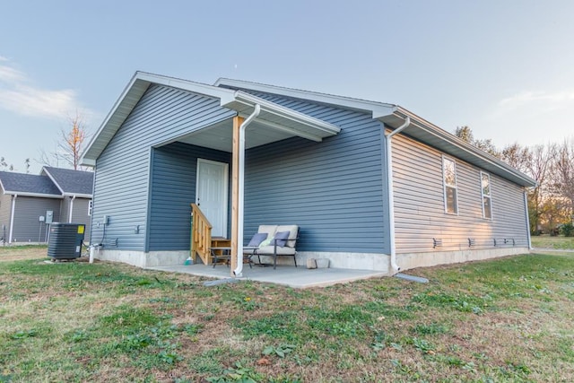 back of property with a lawn, central AC unit, and a patio area