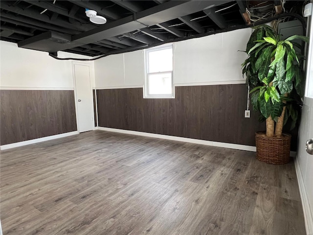 basement featuring wooden walls and dark hardwood / wood-style flooring