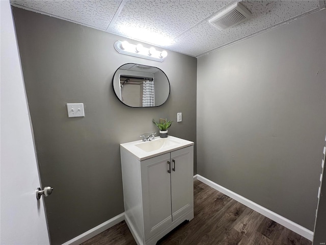 bathroom with a drop ceiling, vanity, and hardwood / wood-style flooring