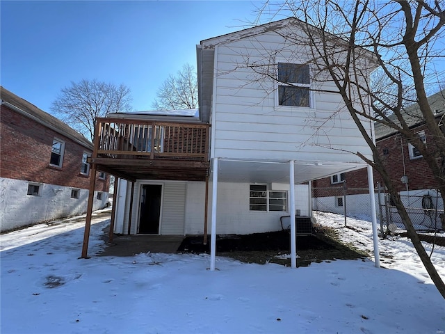 snow covered rear of property with cooling unit and a deck