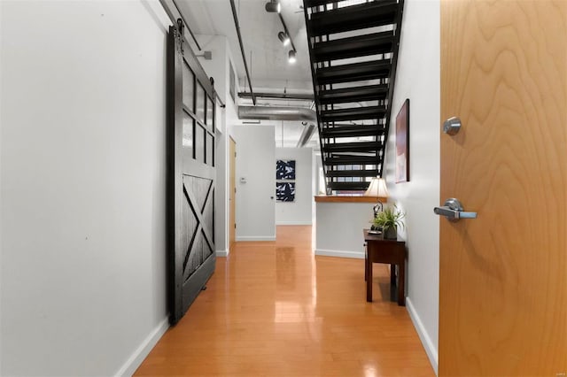 hallway with a barn door and hardwood / wood-style floors