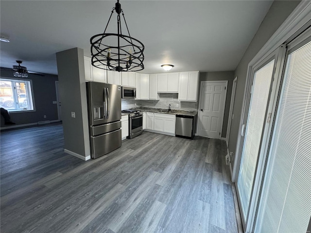 kitchen with pendant lighting, tasteful backsplash, white cabinetry, sink, and stainless steel appliances