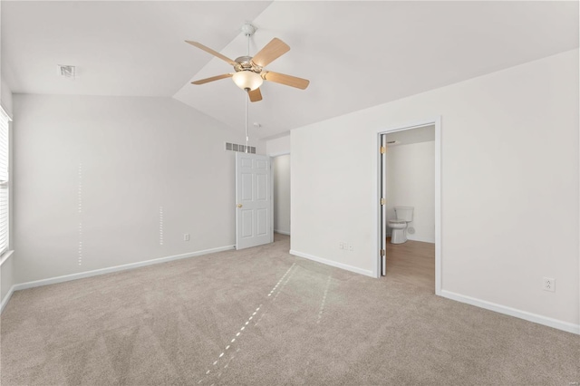 unfurnished bedroom with vaulted ceiling, connected bathroom, light carpet, and ceiling fan