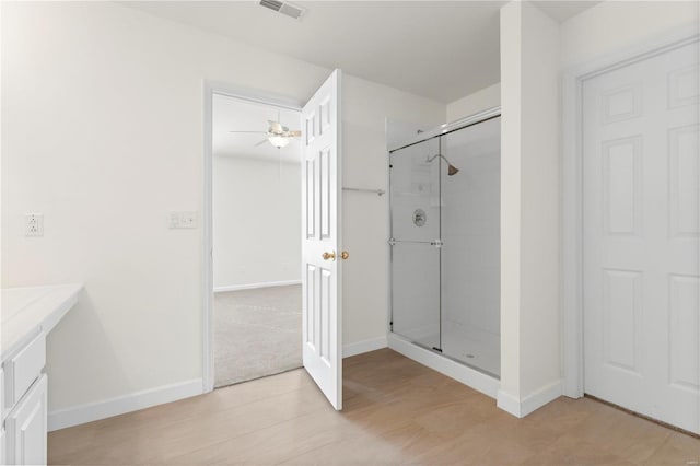 bathroom featuring ceiling fan, wood-type flooring, and a shower with door