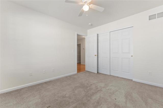 unfurnished bedroom with ceiling fan, light colored carpet, and a closet