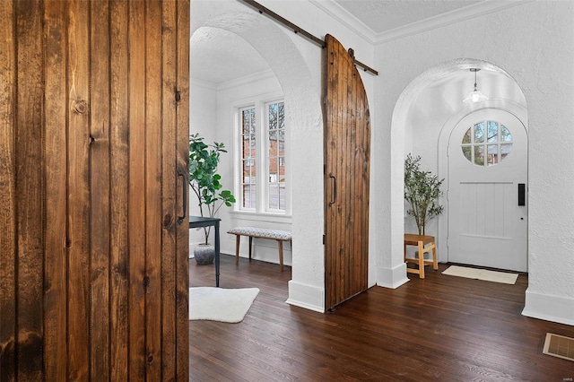 entrance foyer with crown molding, dark hardwood / wood-style flooring, a barn door, and a textured ceiling