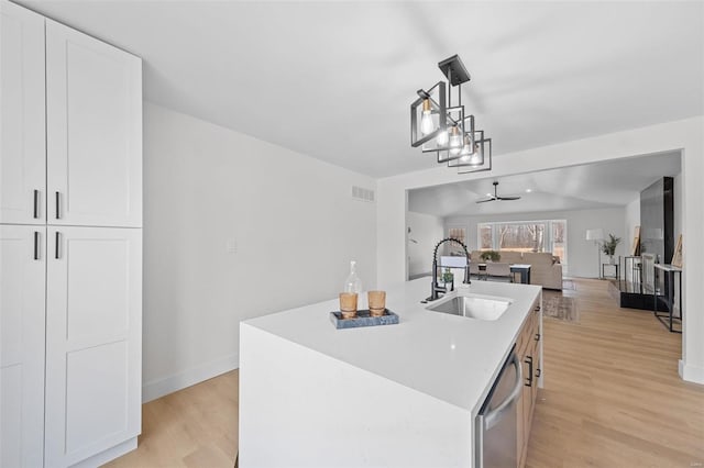 kitchen with sink, white cabinetry, decorative light fixtures, dishwasher, and a kitchen island with sink