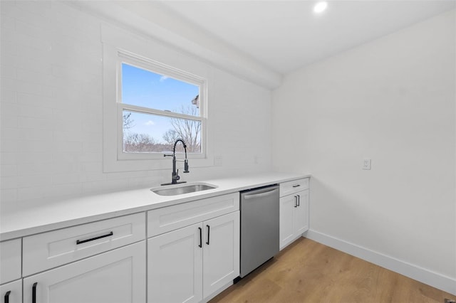 kitchen featuring sink, white cabinetry, tasteful backsplash, stainless steel dishwasher, and light hardwood / wood-style floors