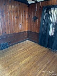 spare room featuring hardwood / wood-style flooring and wooden walls