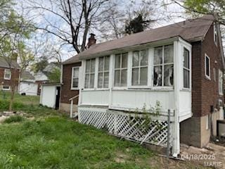 view of side of property featuring a lawn, a chimney, and a sunroom