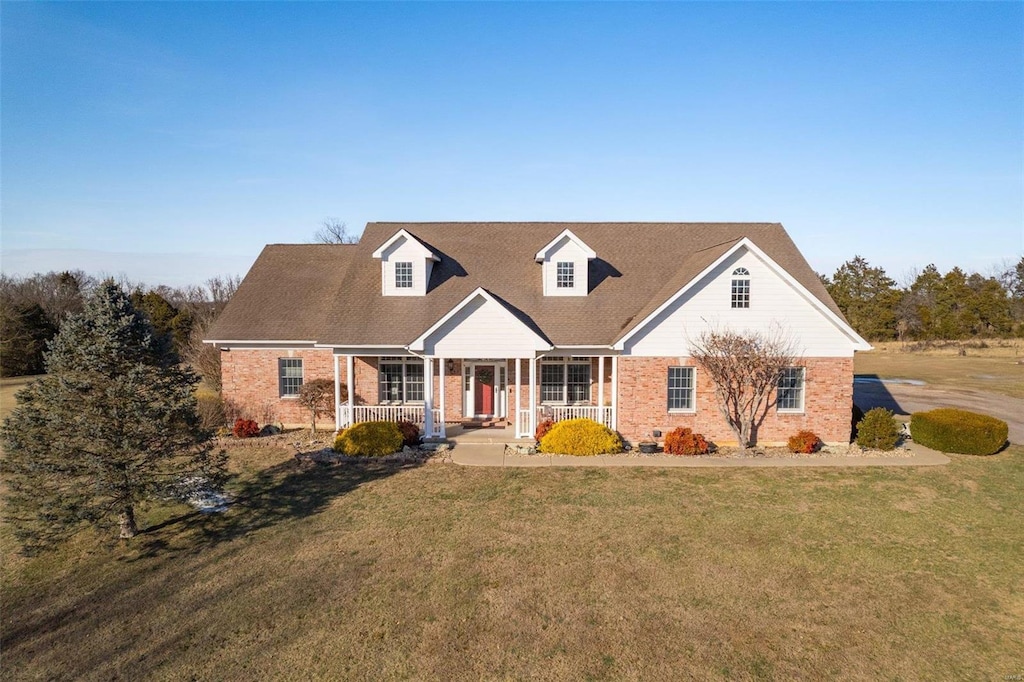 cape cod home featuring a porch and a front yard