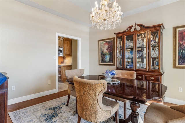 dining space with wood-type flooring and an inviting chandelier