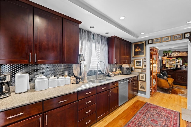 kitchen with sink, decorative backsplash, stainless steel dishwasher, light stone countertops, and light hardwood / wood-style flooring