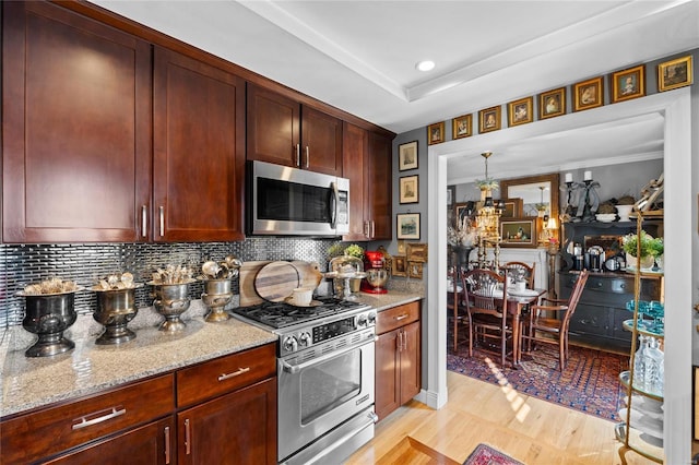 kitchen featuring decorative backsplash, light stone countertops, and appliances with stainless steel finishes