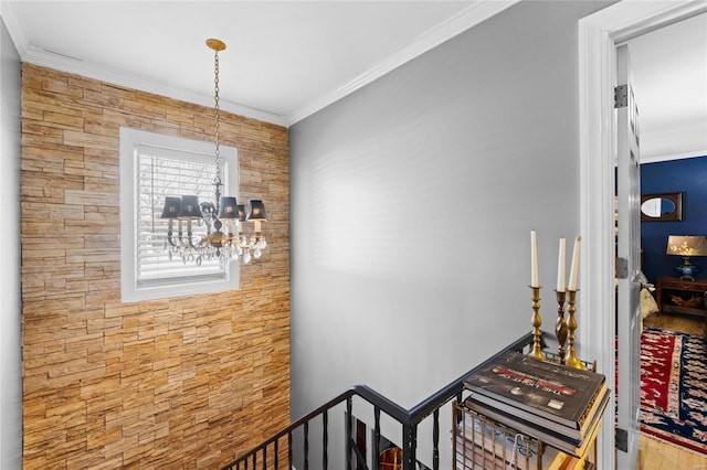 hall with ornamental molding and an inviting chandelier