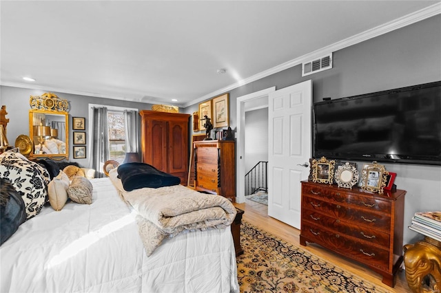 bedroom with ornamental molding and light wood-type flooring