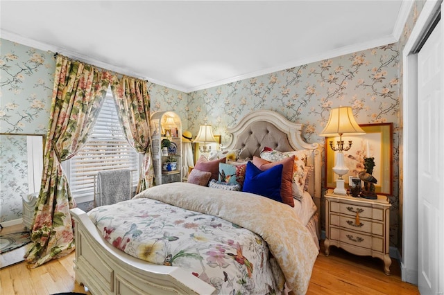 bedroom with crown molding, light wood-type flooring, and a closet