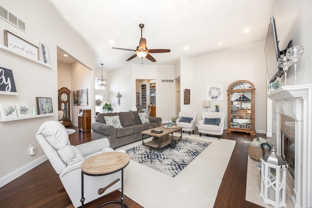 living room with dark wood-type flooring, a premium fireplace, and ceiling fan