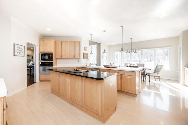 kitchen with hanging light fixtures, a center island, black appliances, light brown cabinets, and light wood-type flooring