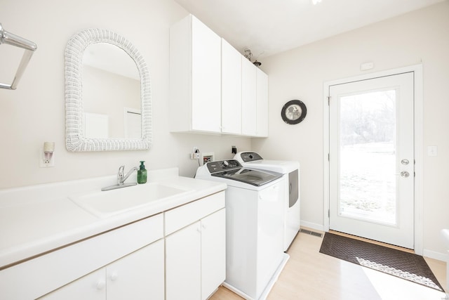 clothes washing area with cabinets, plenty of natural light, separate washer and dryer, and sink