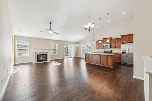 kitchen featuring dark hardwood / wood-style floors, pendant lighting, an island with sink, a high end fireplace, and stainless steel appliances