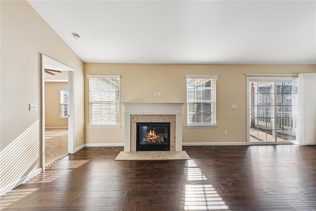 unfurnished living room featuring dark hardwood / wood-style floors, lofted ceiling, a premium fireplace, and a wealth of natural light