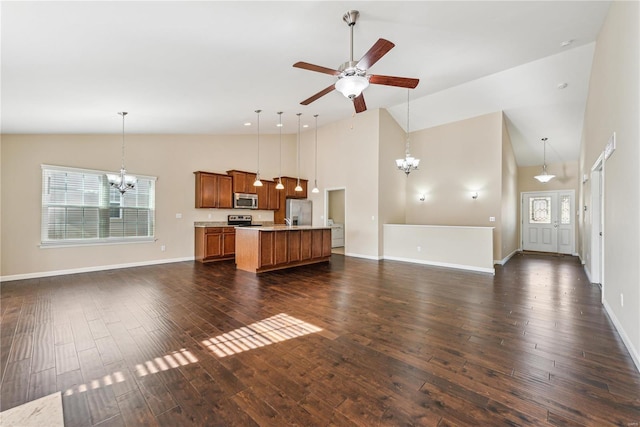 unfurnished living room with dark hardwood / wood-style flooring, ceiling fan with notable chandelier, and high vaulted ceiling