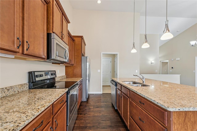 kitchen with sink, hanging light fixtures, stainless steel appliances, dark wood-type flooring, and a center island with sink