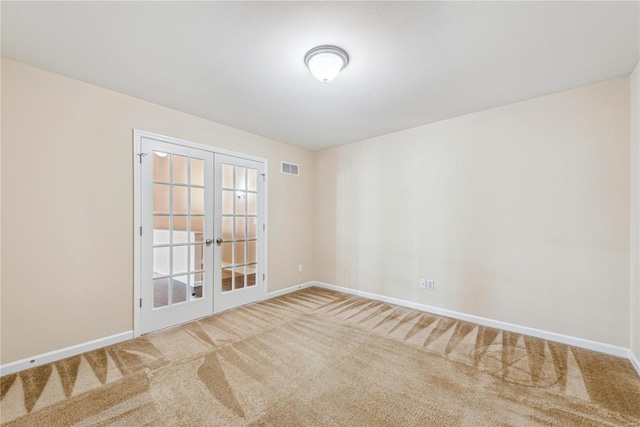 spare room featuring french doors and carpet