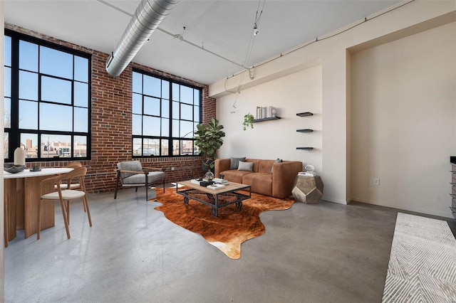 living room featuring a high ceiling, brick wall, and concrete floors