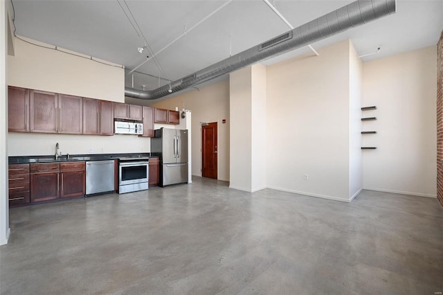 kitchen featuring sink, concrete floors, a high ceiling, and appliances with stainless steel finishes