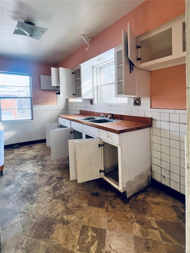 kitchen with wood counters, sink, backsplash, and white cabinets