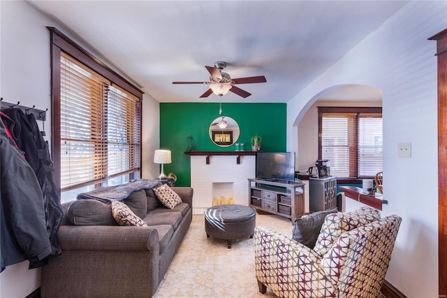 living room featuring a fireplace and ceiling fan