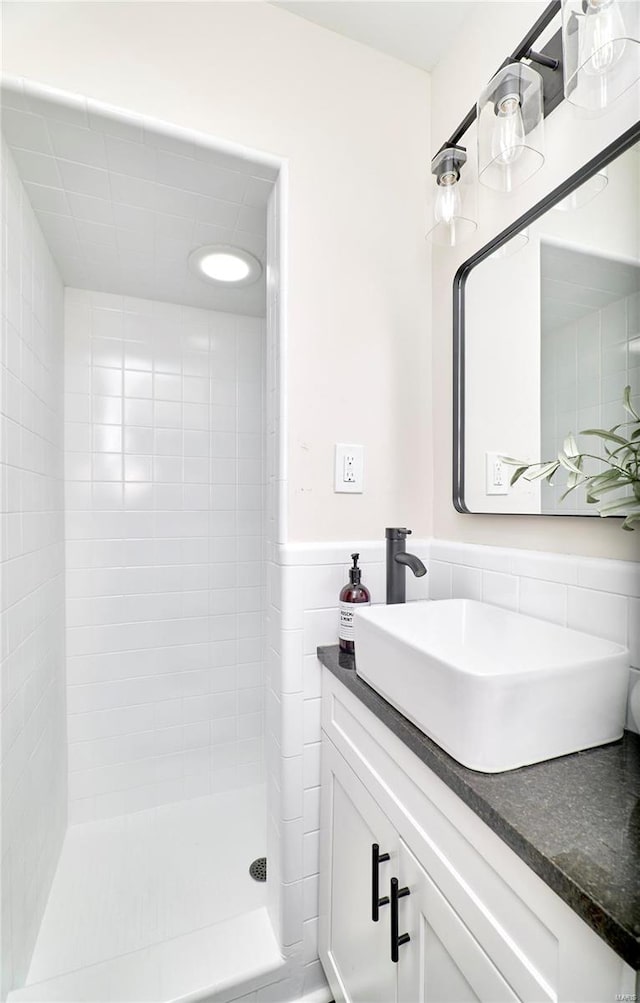 bathroom with vanity, tiled shower, and tile walls