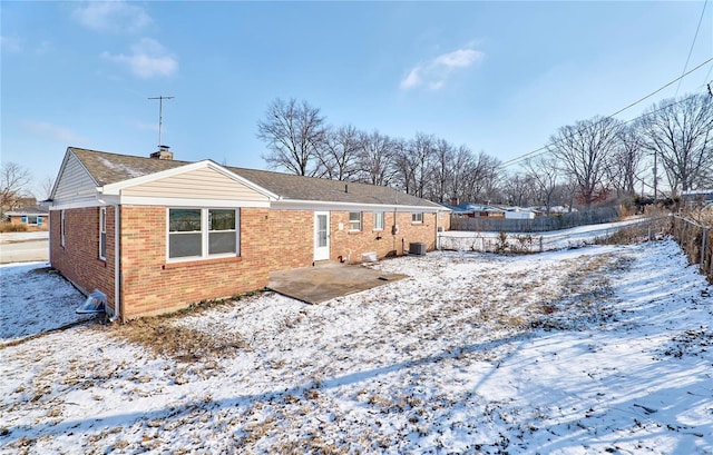 snow covered rear of property with a patio and central air condition unit