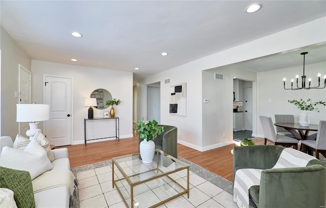 living room with light hardwood / wood-style floors and a notable chandelier