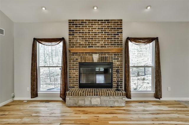 unfurnished living room featuring a brick fireplace and light hardwood / wood-style floors