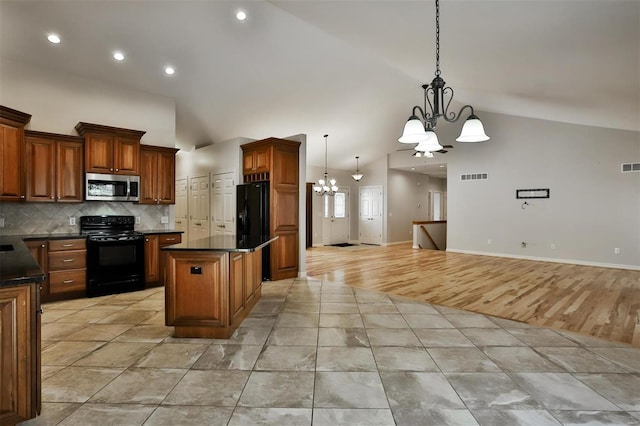 kitchen with a kitchen island, decorative light fixtures, backsplash, a notable chandelier, and black appliances